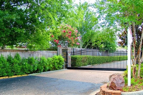 A black gate with a metal fence and a stone pillar in front of it.