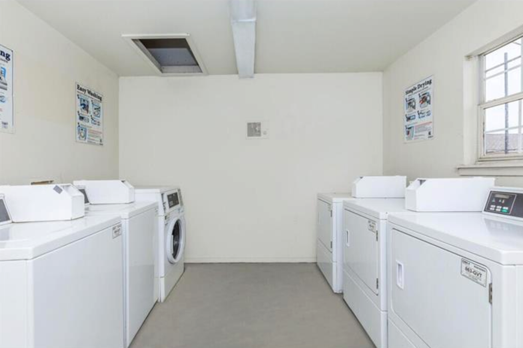 A row of white washing machines in a laundromat.