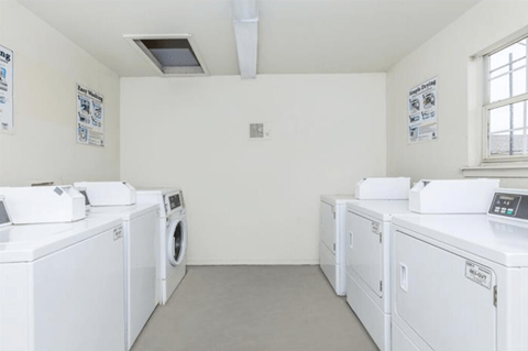 A row of white front load washing machines in a laundromat.