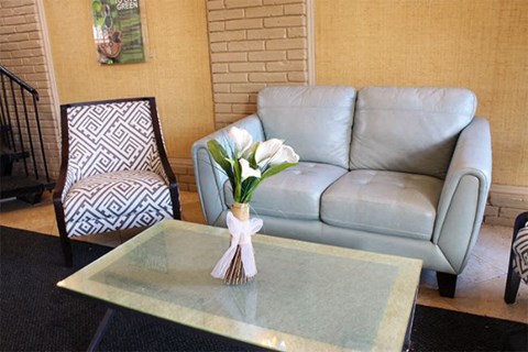 A grey couch with a glass table in front of it.