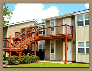 A tan and white two story apartment building with a red staircase.