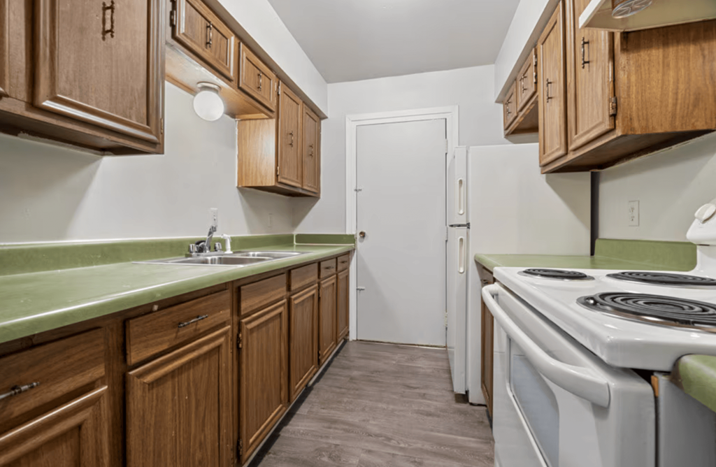 A kitchen with wooden cabinets and a white stove top oven.