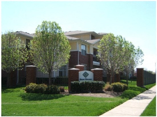 an apartment building with a lawn and trees in front of it