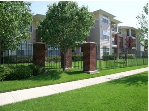 an apartment building with a sidewalk and a fence