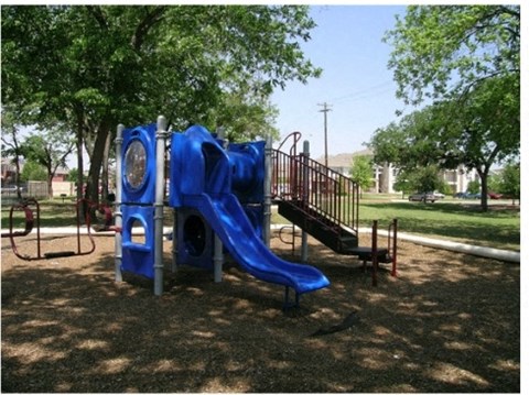 a playground with a blue playset and a slide