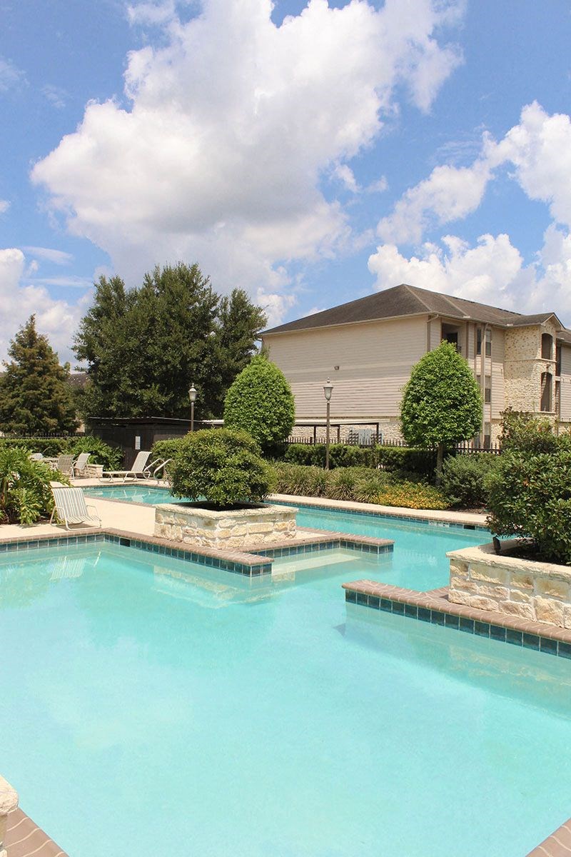 a large swimming pool with a house in the background
