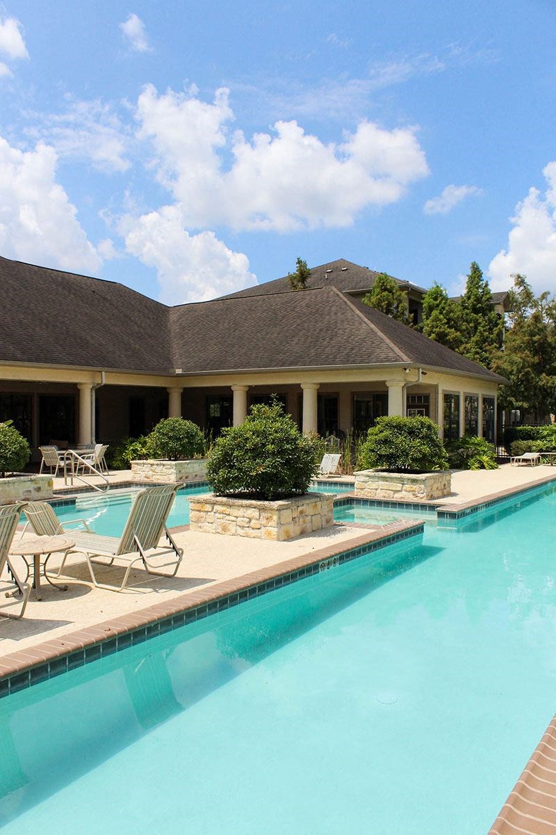 a large swimming pool in front of a hotel with chairs