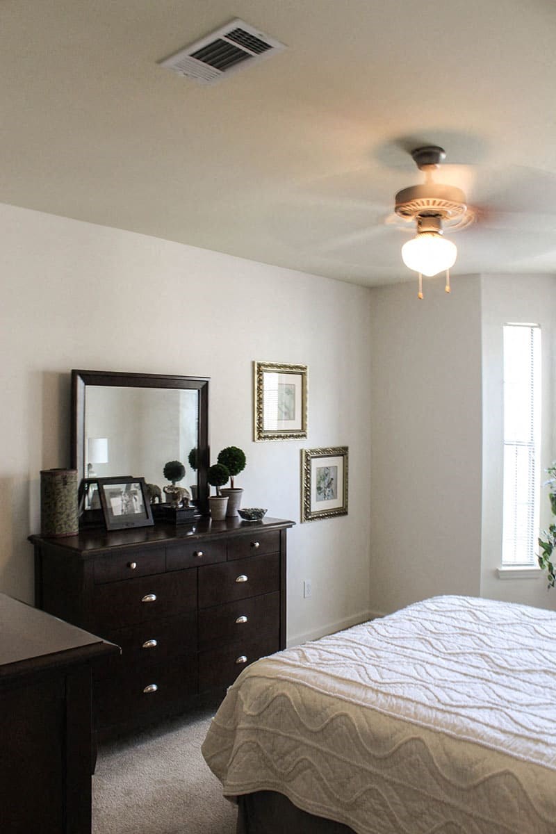 a bedroom with a bed and a dresser and a ceiling fan