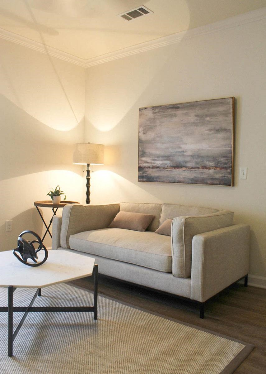 a living room with a couch and a painting on the wall