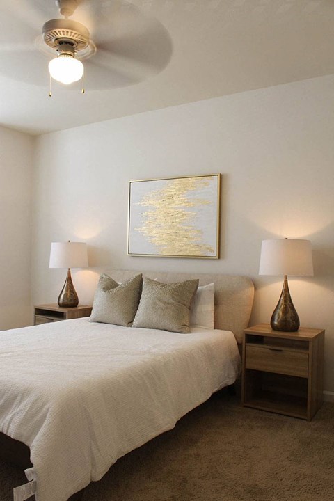 a bedroom with a white bed and a ceiling fan