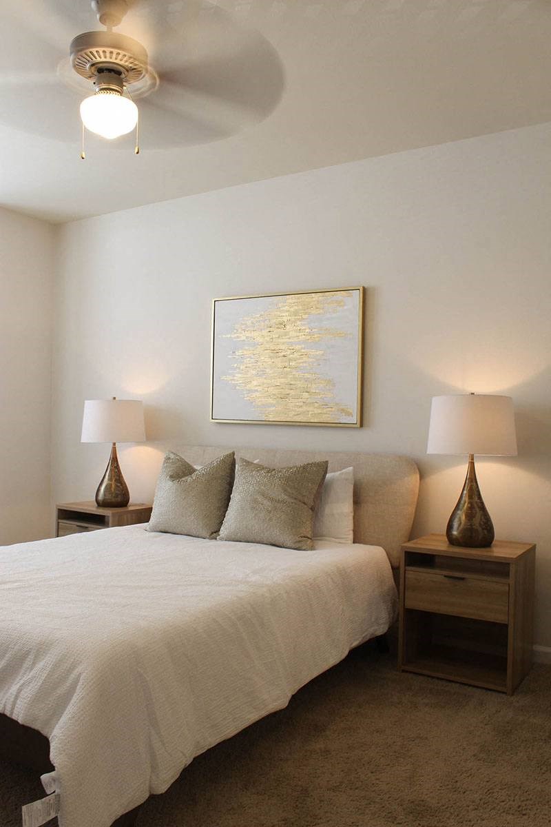 a bedroom with a white bed and a ceiling fan