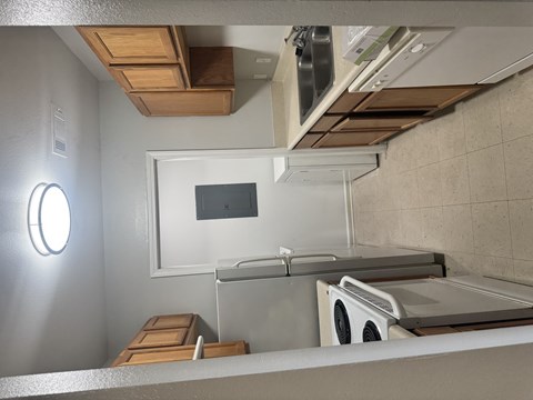 A small kitchen with a microwave, oven, and a fan.