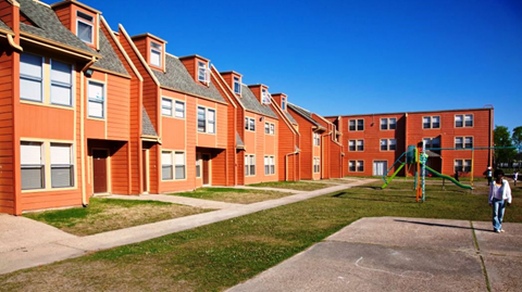 A person walks in front of a building with red brick and white trim.