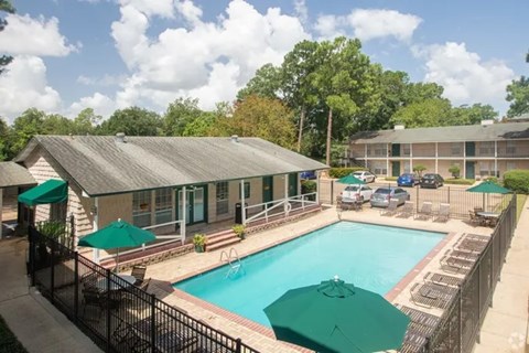 A pool surrounded by a black fence with green umbrellas.