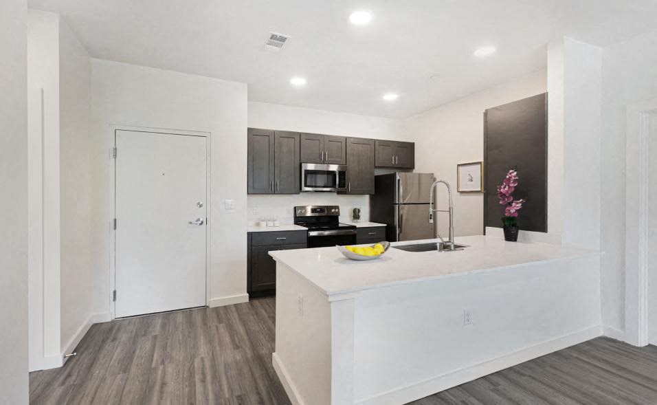 A kitchen with a white island and dark wood floors.