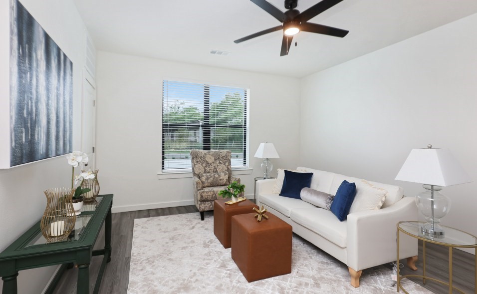 A living room with a white couch, a green coffee table, and a ceiling fan.