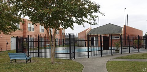 A black fence surrounds a pool and a building.