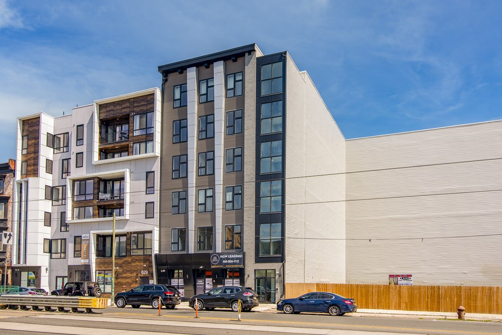 A modern multi-story building with cars parked in front.