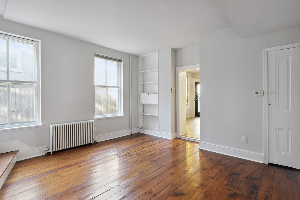 an empty room with hardwood floors and two large windows