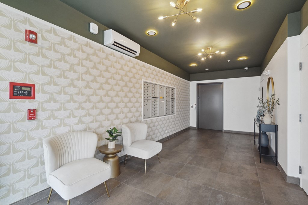 a lobby with two white chairs and a white wall with a door