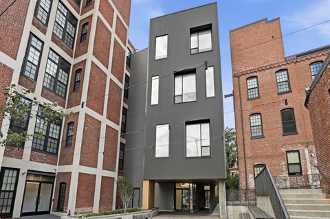 A modern building with a black facade stands between two older red brick buildings.