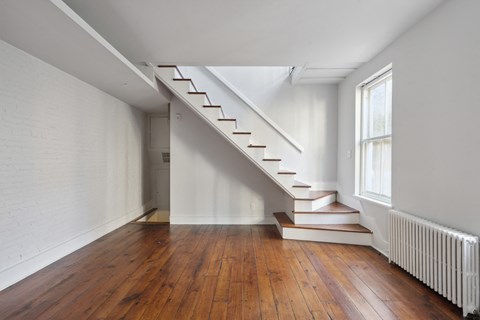 a stairwell in a home with hardwood floors and a large window