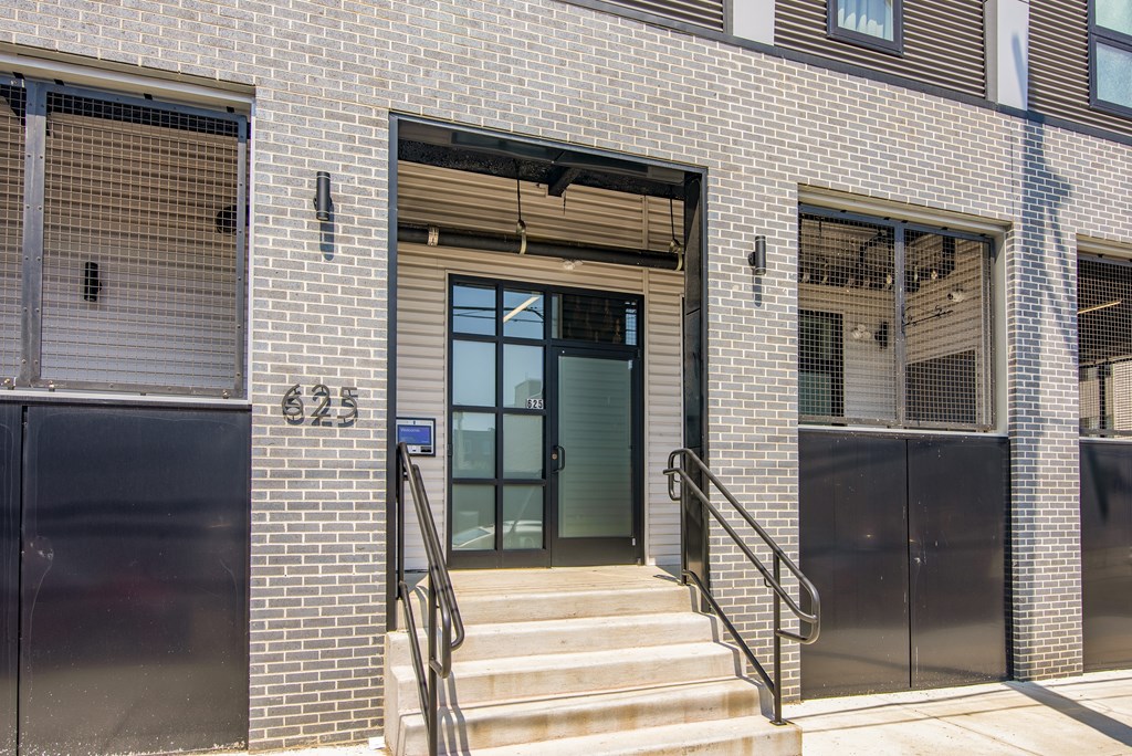 The image shows a building with a grey brick facade and a green door.