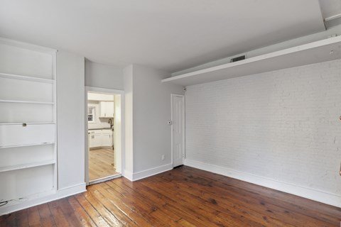 a bedroom with hardwood floors and white walls