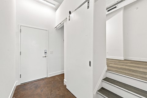 A white door is on the left and a staircase is on the right.