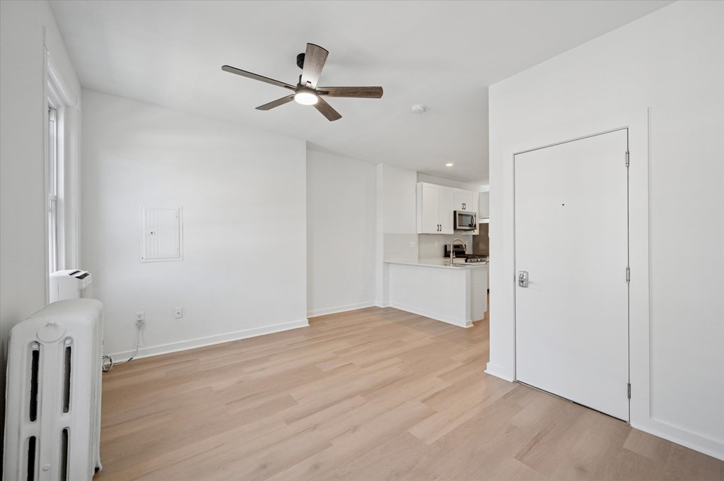 A room with a ceiling fan and a radiator on the floor.