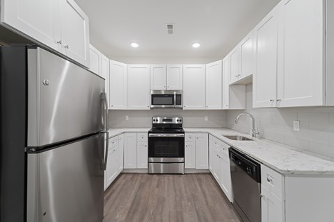 A modern kitchen with white cabinets and stainless steel appliances.
