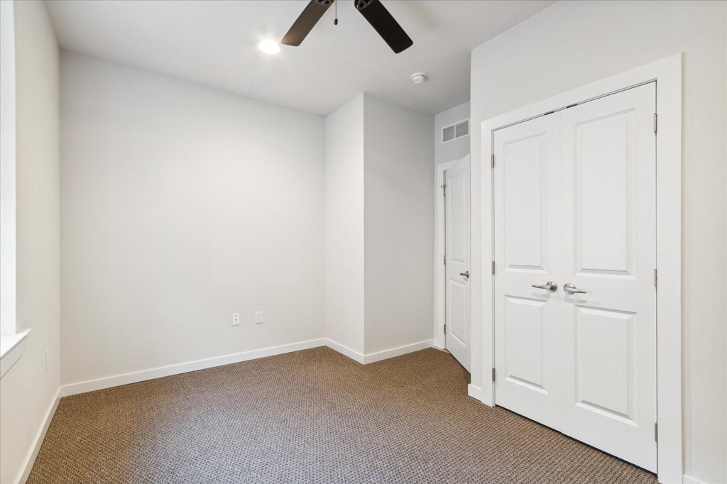 an empty room with white doors and a ceiling fan