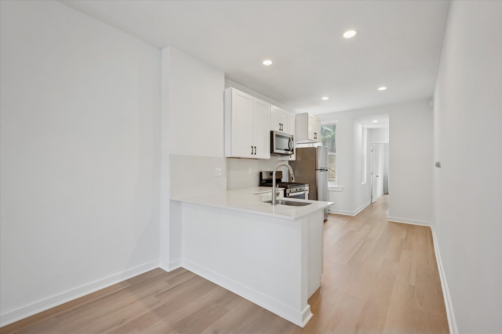 A kitchen with white cabinets and a wooden floor.