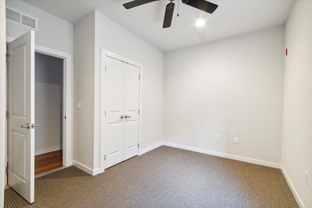an empty room with white walls and a ceiling fan