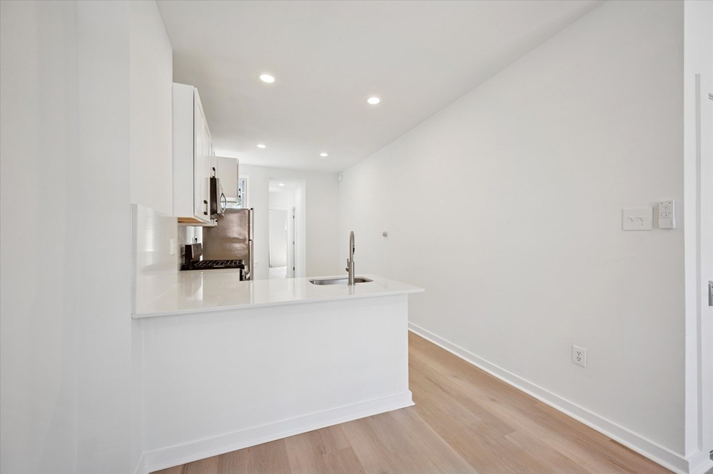 A kitchen with white cabinets and a white island.