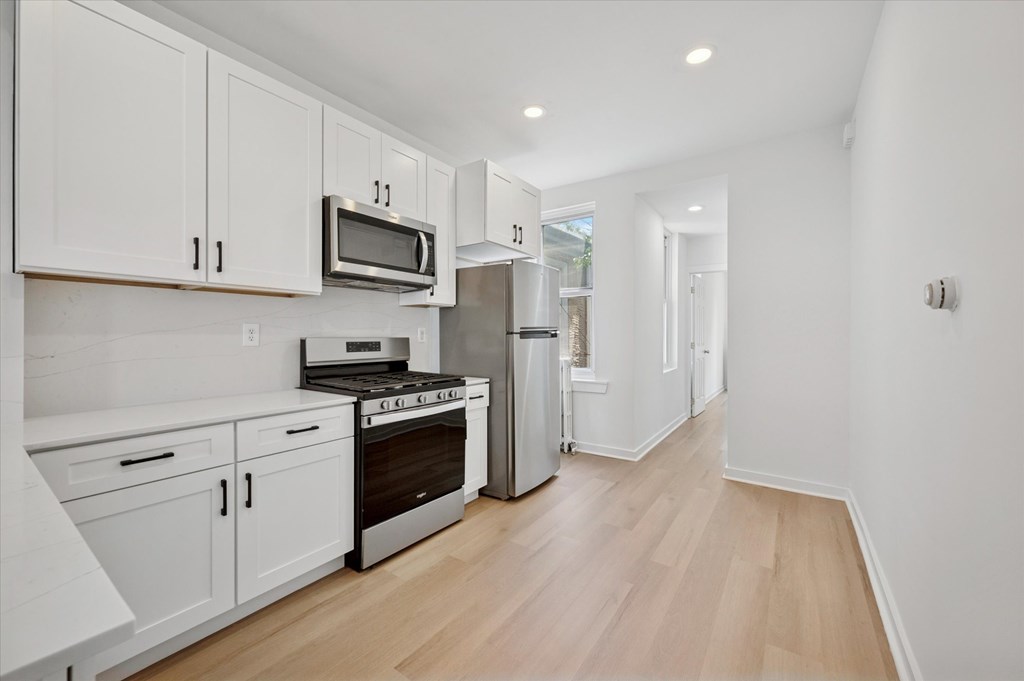 A kitchen with white cabinets and appliances.