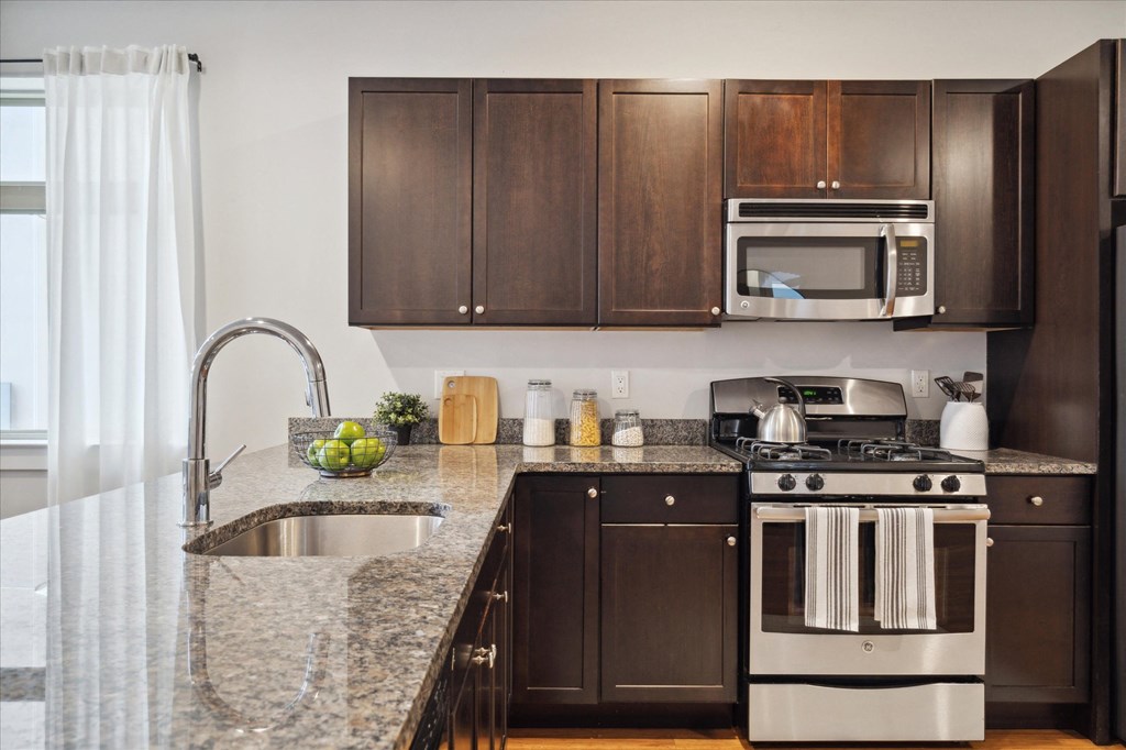 a kitchen with dark wood cabinets and granite counter tops and a sink