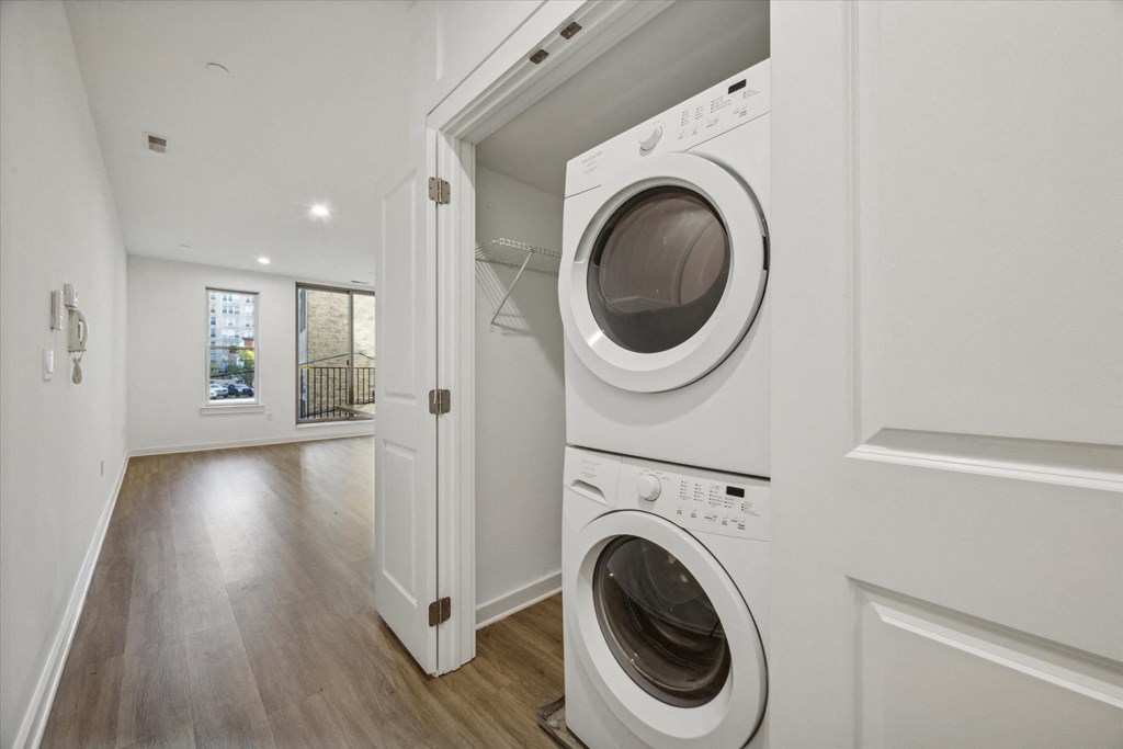 A white washing machine is in a laundry room with a door open.