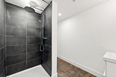 A bathroom with a black tiled shower and a white bathtub.