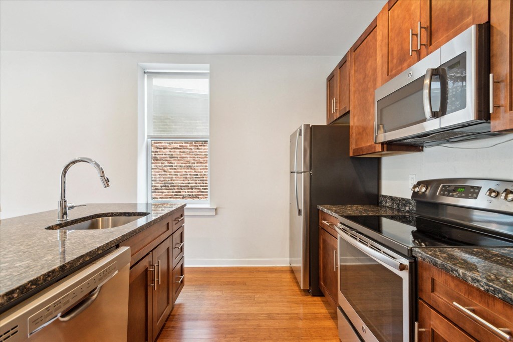 an empty kitchen with stainless steel appliances and wooden cabinets