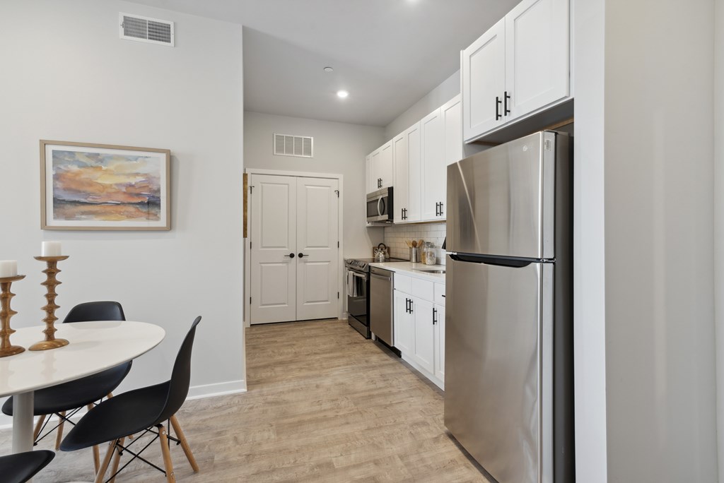 A kitchen with a refrigerator, table and chairs.