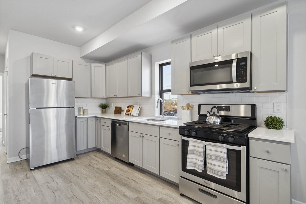 a white kitchen with stainless steel appliances and white cabinets