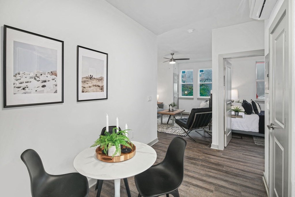 a small table with three chairs in a room with a bedroom in the background