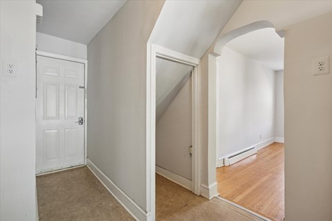 A white door is in a hallway with a light switch on the wall.