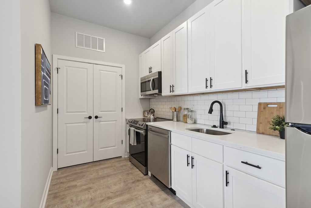 A kitchen with white cabinets and a wooden cutting board on the counter.