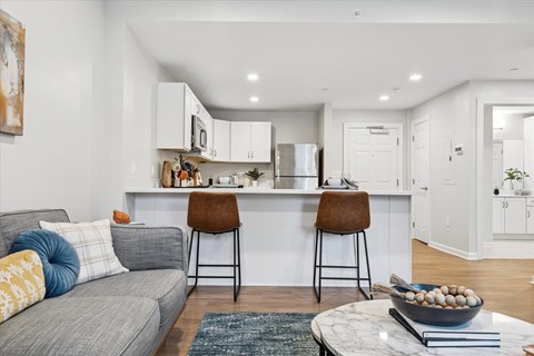 A modern kitchen with a grey couch and a marble table.