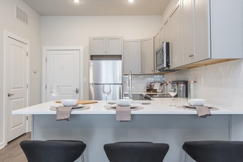 a kitchen with a white counter top and black chairs