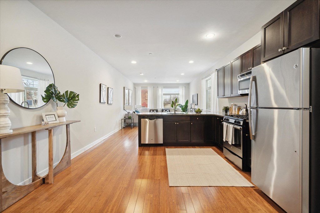 a large kitchen with stainless steel appliances and a wooden floor