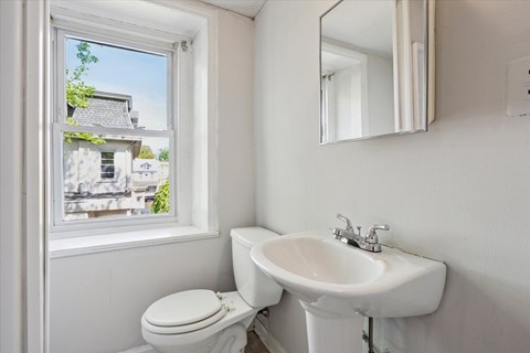 A white toilet and sink in a bathroom with a window.