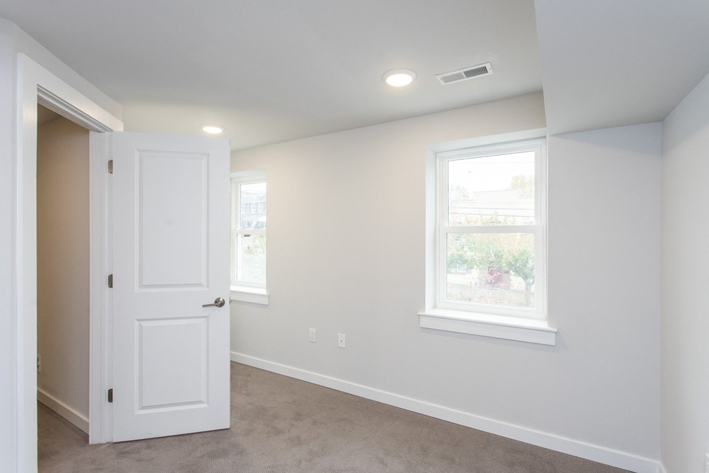 a bedroom with a white door and two windows